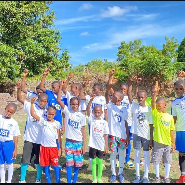 Kids in Haiti raising their fists in donated jerseys